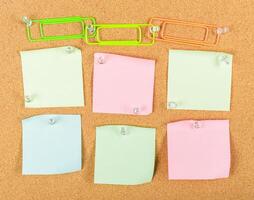 Colorful sticky notes and paper clips arranged on a corkboard for organizing ideas and reminders in an office setting photo