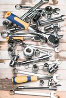 Collection of various hand tools organized on a wooden surface in a workshop setting during daylight photo