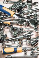 Various metal tools and instruments scattered on a wooden surface in a workshop setting photo