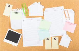 Organized workspace with various notes, documents, and a polaroid on a cork board for effective planning and reminders photo
