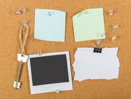 Collection of notes and a key displayed on a cork board with various pinned items for organizing thoughts and reminders photo