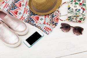 Stylish summer accessories arranged on a flat surface with a colorful bag, shoes, hat, sunglasses, and smartphone ready for a day out photo