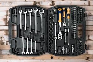 Tool set arranged neatly in a black case on a wooden surface showcasing a variety of wrenches and sockets photo