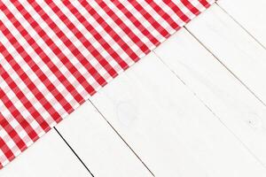 Table setting on a white wooden surface with a red and white checkered cloth for a casual dining experience photo