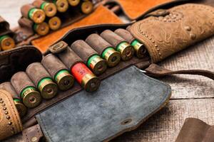 Leather cartridge belt filled with shotgun shells and rustic wooden background in a shooting range setting photo