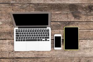 Laptops, tablets, and smartphones arranged on a wooden table for digital workspace setup photo
