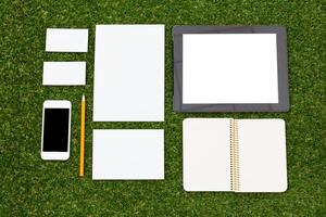 Creative workspace setup with stationery on grass during a sunny day photo