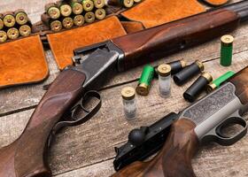 Rifles and shotgun shells arranged on a rustic wooden surface for ammunition preparation and hunting activities photo