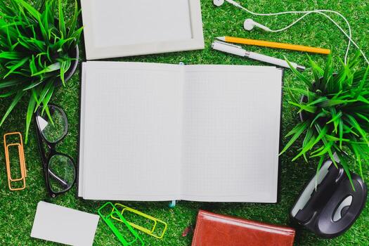 Items for a productive workspace with an open notebook, stationery, and greenery on a textured surface photo