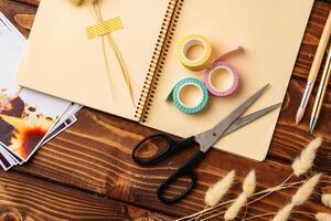 Crafting materials arranged on a wooden table with scissors, tape, and a notebook for creative projects photo