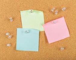 Colorful sticky notes pinned on corkboard with pushpins in an organized workspace for reminders photo