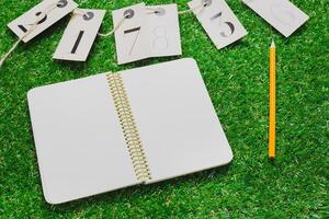 Blank notebook and numbered tags on green grass background for planning and organization photo