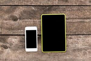 Comparison of a smartphone and tablet placed on a rustic wooden surface highlighting their sizes and shapes photo