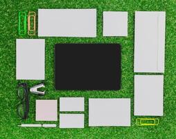 Office workspace layout with stationery items on green turf background during daylight photo