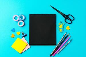 Creative workspace with colorful stationery arranged on a bright blue background for art projects photo