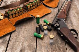 Shotgun and ammunition arranged on a wooden surface ready for hunting or shooting practice in an outdoor setting photo