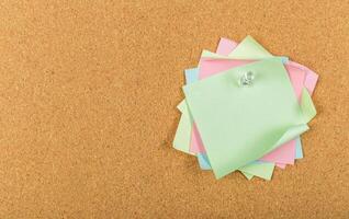 Colorful sticky notes arranged on a cork board for reminders and organization in an office setting photo