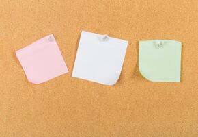 Colorful sticky notes pinned on a corkboard for reminders and organization in a workspace setting photo