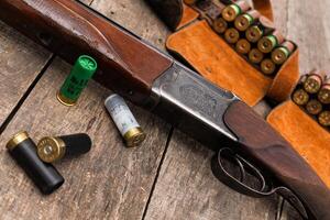 Vintage shotgun with ammunition set on rustic wooden table in hunting environment photo