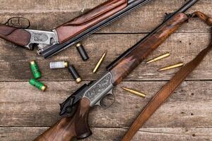 Hunting equipment arranged on a wooden surface with camouflage gear and shells in the early morning light photo