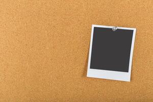 Blank instant photo rests on cork board waiting for memories to be captured and displayed over time