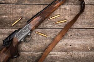 Detailed wooden hunting rifle on rustic wood table with ammunition scattered around photo
