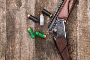 Vintage shotgun and ammunition resting on wood surface in a rustic setting during daylight hours photo