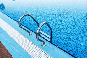 Crystal clear swimming pool with stainless steel handrails on a sunny day photo
