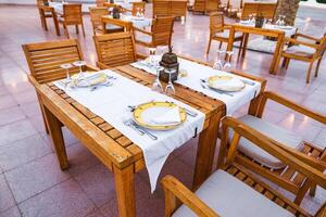 Outdoor dining setup with wooden tables and elegant tableware in a warm atmosphere during sunset photo