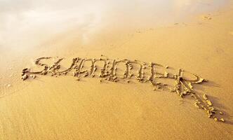Writing summer in sand on a sunny beach reflecting the joy of warm weather and vacation vibes photo