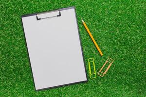 Blank notepad and stationery items on artificial grass for creative planning and organization photo