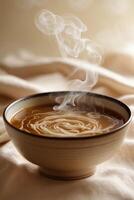 Warm bowl of creamy coffee with swirling steam against a soft fabric backdrop in a cozy setting photo