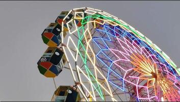 A ferris wheel is lit up in a colorful display video