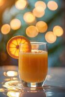 Refreshing orange drink served in a clear glass on a reflective surface with glowing bokeh background photo