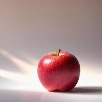 Bright red apple stands alone on a soft surface with gentle light casting shadows in the background photo