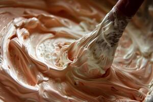 A spoon is used to mix a creamy white and pink frosting photo