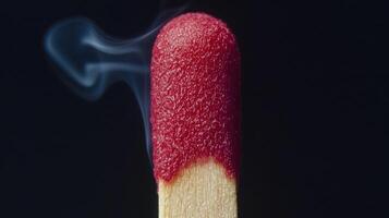 Bright red matchstick head ignites, producing smoke that gently spirals upward against a dark backdrop, illustrating the process of combustion and fire photo