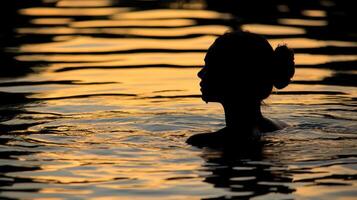 Silhouette of a woman in the water at sunset photo