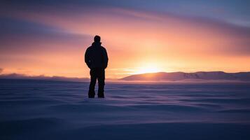 A man standing in the snow at sunset photo