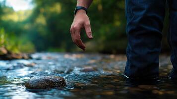 A person standing in a stream with their hand out photo
