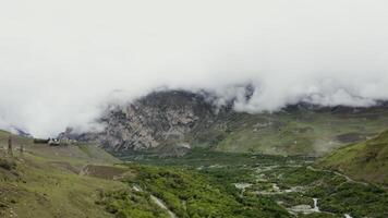 View of a mountain valley with cliffs covered with clouds, forests, fields, roads and residential settlements in the lowlands. mountain nature of the Caucasus photo
