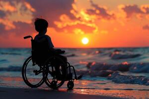 A child in a wheelchair is sitting on the beach at sunset photo