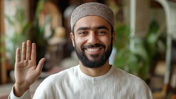 Friendly young muslim man waving hand and smiling happily photo