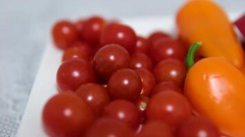Yellow bell pepper slowly spins, resting on plate of vibrant red and yellow cherry tomatoes video