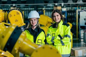 Female engineers working with industrial robots in a factory setting during daytime operations photo
