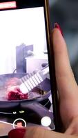 blogger girl films food on mobile phone fry meat in a frying pan Adding smashed garlic and thyme to beefsteak into frying pan video