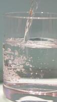 turquoise table Pouring drink water to to glass of water. pouring fresh clean drinking water into glass, splashing in glass on white background, soft focus with slow motion. Concept of drinking video