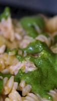 Fusilli pasta cooked with tomatoes and basil in dark gray bowl, rotating isolated on black background, turning, close-up macro. video