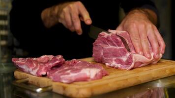 A butcher cuts a large piece of selected meat with a knife on wooden board. Selected pork. video