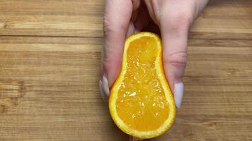 Close up of hands squeezing orange for juice. Human using their hands to squeeze half citrus to make the orange juice into the glass. Making orange juice pressing half of orange. video